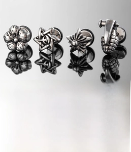 Macro shot of silver titanium steel studs featuring flower and star patterns