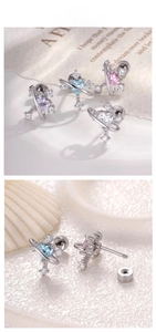 Detail showing heart-shaped zircon saturn earrings with screw-back design and cross motif