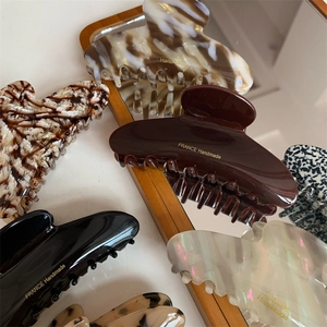Close-up of elegant curved hair claws with tortoise shell pattern and France Handmade text