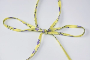 Detailed close-up of yellow floral fabric tie with purple flower pattern and soft texture