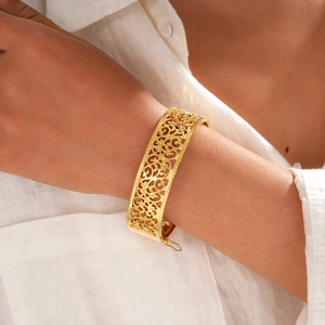Detailed close-up of a vintage golden hollow pattern bangle with secure pin clasp