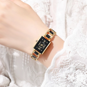Dettaglio dell'orologio al quarzo quadrato oro e nero su un polso femminile