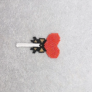 Handmade Miyuki bead heart lollipop charm for jewelry making on grey plush background
