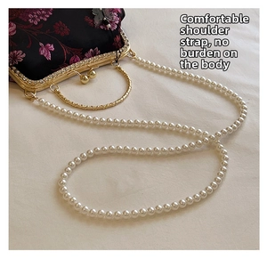 Detail of floral embroidery on black brocade bag with pearl strap and metal clasp