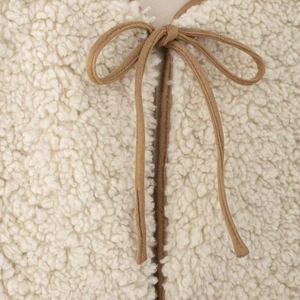 Gilet chic en peau de mouton beige avec un détail de nœud papillon marron chameau