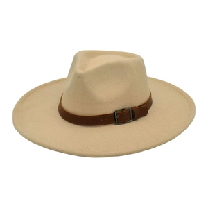Détail d'un chapeau fedora beige à large bord avec boucle en cuir sur fond blanc