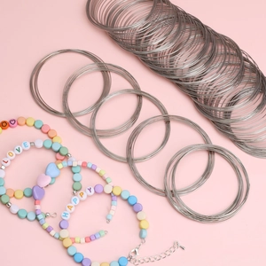Detail of silver memory wire coils and handmade beaded bracelets on pink background