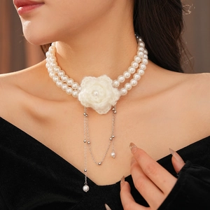 Close-up of double-layer pearl necklace featuring a white knit flower and silver tassels