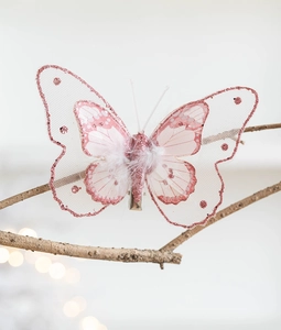 Detail of pink mesh butterfly ornament with glitter and feathers on a branch