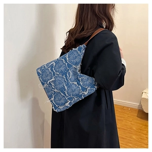 Model showcasing a vintage blue denim tote bag with frayed patterns and brown shoulder straps