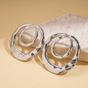 Detailed close-up of silver irregular double-hoop earrings with lava texture