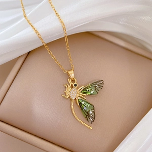 Macro shot of gold dragonfly pendant with green wings and zircons in a jewelry box