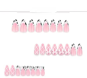 Detail of pink almond press-on nails with cow prints and 3D white bow decorations