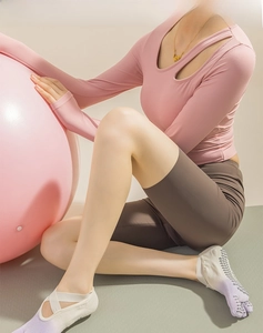 Pink long sleeve cutout top and brown high waist yoga shorts set on fitness mat