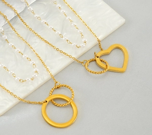 Détail de colliers dorés double rang avec cœur évidé, cercles et perles blanches