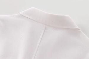 Detailed view of the neckline and back seam stitching on a white linen blend shirt