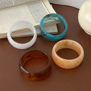 Macro shot of resin bangles with marble texture displayed on leather and a book