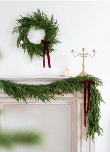 Close-up of green Christmas garland with velvet red bows and silver balls on mantel