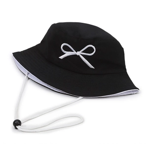 Classic black and white reversible bucket hat with elegant bow embroidery and windproof cord