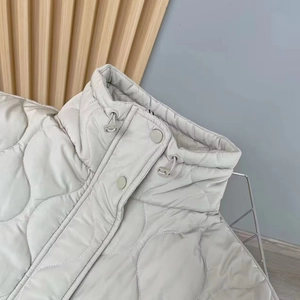 Close-up of light grey quilted vest showing stand collar and adjustable drawstring detail