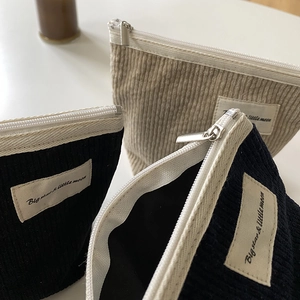 Detail of vintage corduroy cosmetic pouches in beige and black with zipper and label