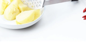 Vue détaillée du presse-purée en inox écrasant des pommes de terre cuites