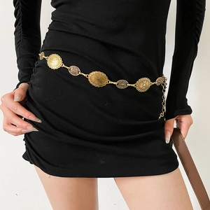 Detailed close-up of retro gold metal waist chain with embossed oval texture on black dress