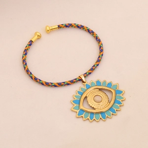 Detailed macro view of the colorful woven cord and golden evil eye pendant with blue enamel