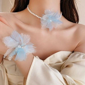 Detail of light blue mesh flower necklace and pearl bracelet set worn on neck and wrist