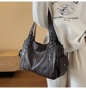 Detail of dark brown faux leather tote bag showing large capacity and side pocket on model