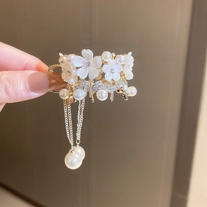 Detail of floral hair claw with sparkling rhinestones, pearls and golden tassels