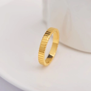 Macro detail of 18k gold plated ribbed ring with vertical gear-like texture on white ceramic