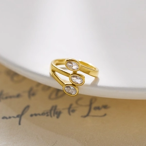 Detail of gold layered open ring with three oval zircons on white ceramic tray
