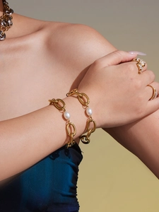 Detail of 18k gold plated chain bracelet with pearls and rings on model wrist