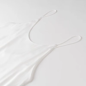 Dettaglio dell'abito in raso bianco con spalline sottili e tessuto effetto seta