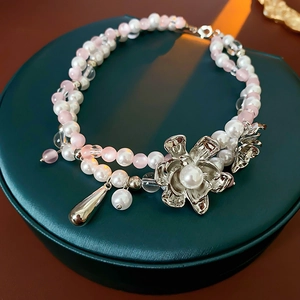 Detail of beaded necklace with pink opal beads, white pearls, and silver flower pendant