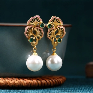 Detail view of enamel ginkgo leaf earrings with white pearls and green gemstones