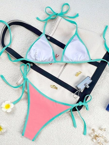 Detailed flat lay of a two-piece colorblock bikini with pink and mint green beach accessories