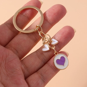 Detail of gold metal keychain with purple heart round charm and white heart pendants