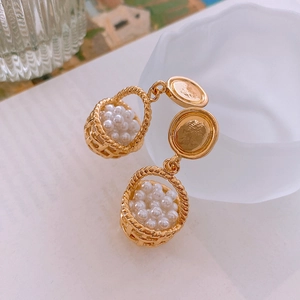 Macro view of vintage gold woven basket earrings with white pearls and stud detail