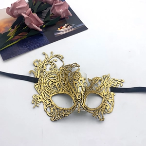 Close-up of gold lace masquerade mask with intricate cutout patterns and black ribbons