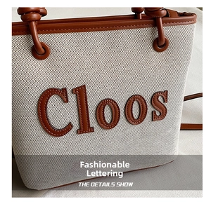 Detail shot of the canvas tote bag with brown leather letters and refined stitching