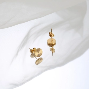 Detail of 18K gold-plated round earrings with engraved sunburst texture and butterfly backs