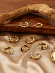 Detail view of gold twisted hoop earrings with colorful gemstones on silk fabric