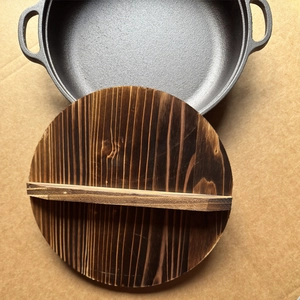 Pre-seasoned cast iron skillet with natural wooden lid and dual-handle design for cooking