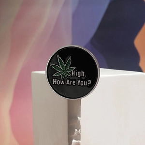 Enamel pin badge with green leaf design and High How Are You text on black background