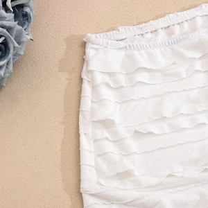 Détail de la jupe blanche à volants étagés avec taille élastique et texture légère