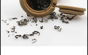 Macro shot of an open brown silicone poop-shaped tea infuser with loose tea leaves
