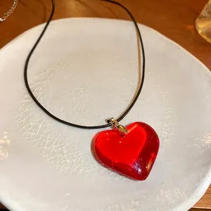 Collier minimaliste avec pendentif cœur en verre rouge et cordon noir sur céramique