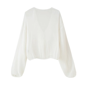 Detail of white V-neck long sleeve blouse featuring ruffled edges and tied waist design